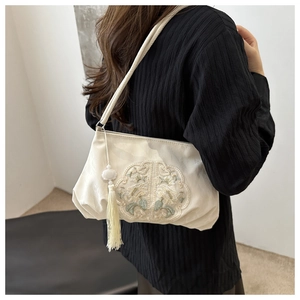 Detail of white embroidered shoulder bag with floral motifs and silk fringe tassel
