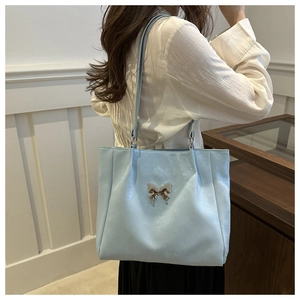 Détail du sac cabas en simili cuir bleu clair avec ornement papillon en métal argenté