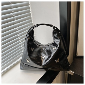 Close-up of black glossy leather moon bag with silver butterfly metallic details