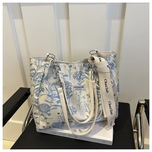 Detailed view of canvas tote bag with blue floral embroidery and branded jacquard strap