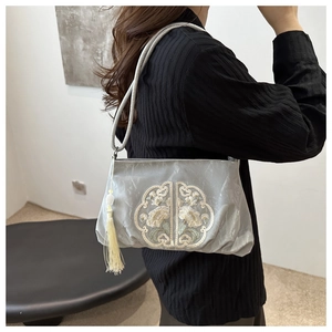 Detail of grey silk shoulder bag with white floral embroidery and pearl tassel