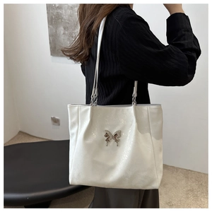Détail du sac cabas blanc perle avec cuir texturé et boucle en nœud métallique