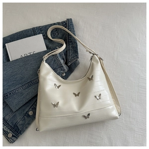 Detail of cream leather shoulder bag featuring silver metal butterfly embellishments