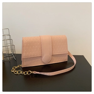 Détail du sac à bandoulière rose avec texture géométrique embossée et sangle en chaîne dorée