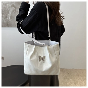 Détail du fermoir papillon argenté sur un grand sac cabas blanc en cuir brillant chic