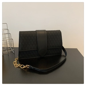 Détail du sac à rabat noir avec motifs triangles gaufrés et chaîne dorée