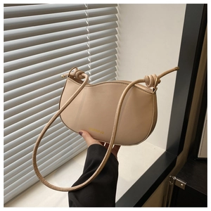 Detail of beige shoulder bag featuring a unique wavy edge and knotted strap design