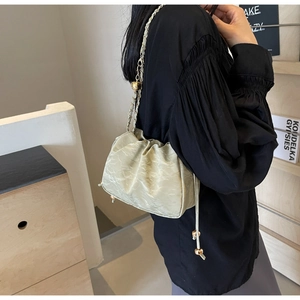 Detail of light green ruched bucket bag with gold metal ball drawstring and chain strap