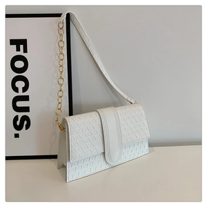 Détail d'un sac à rabat blanc en cuir à gaufrage géométrique et chaîne dorée