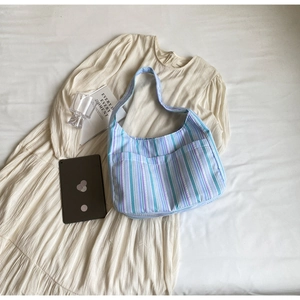 Detail of blue striped nylon hobo bag featuring large front pocket on white fabric