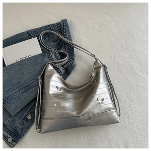 Detailed macro view of silver moon bag featuring metallic butterfly studs and pleated texture