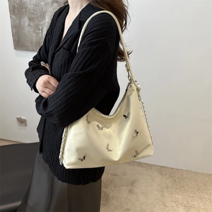 Cream hobo bag with silver metal butterflies and chain strap worn by a model