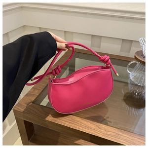 Detail of rose pink glossy leather handbag with curved top and gold metallic hardware