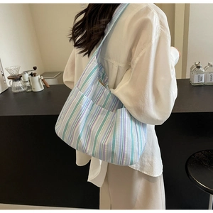 Detail of striped nylon tote bag showing textured pleats and side pocket on shoulder strap