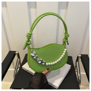 Detail of bright green half-moon bag with pearl heart chain and knotted handle