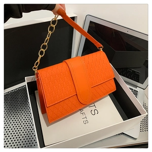 Détail d'un sac à bandoulière orange avec texture géométrique et chaîne métallique dorée