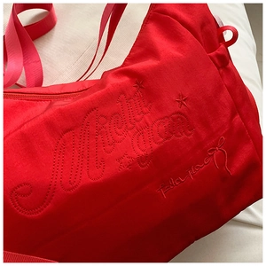 Detailed close-up of Michigan letter embroidery and star pattern on red canvas tote bag