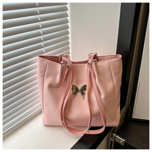 Détail du grand sac cabas rose avec décoration papillon en métal et texture cuir PU mat