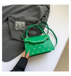 Detail view of green quilted handbag with heart rivets and wavy flap edge design