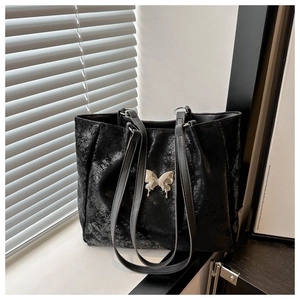 Détail du sac cabas noir avec texture craquelée et ornement papillon en métal argenté