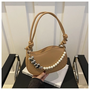Close-up of khaki leather underarm bag with decorative pearl and silver heart chain