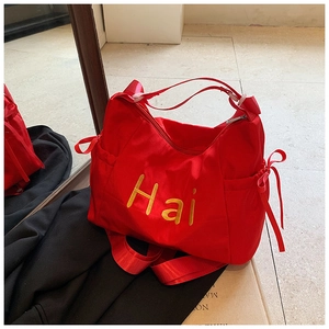 Detailed view of red canvas tote bag with yellow Hai embroidery and bow drawstring pockets