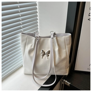 Détail d'un sac cabas blanc avec un grand fermoir papillon en métal argenté et brillant