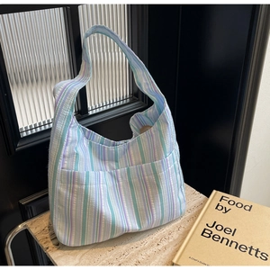 Detail of striped nylon tote bag with side pockets on a stone surface and glass background