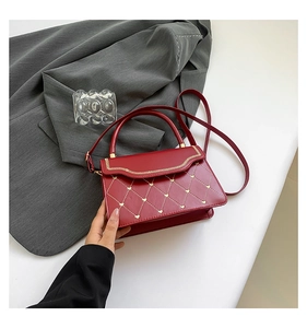 Detail of red leather crossbody bag with golden heart embroidery and metal zipper trim