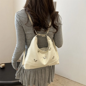 Cream-colored hobo shoulder bag with silver butterfly charms and elegant leather texture
