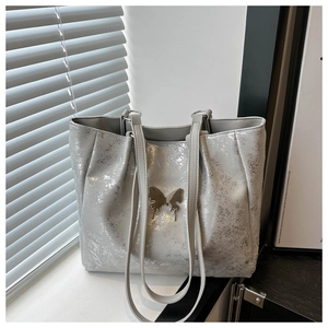 Détail de la texture argentée craquelée et de l'ornement papillon sur le sac cabas femme