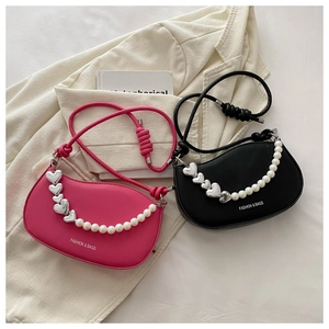 Detail of crescent shoulder bags with decorative pearl and metal heart chain