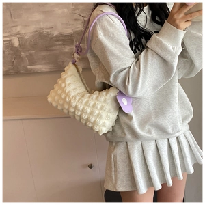 Close-up of a white bubble textured hobo bag with purple shoulder strap and flower charm