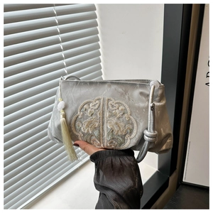 Detail of silver satin cloud bag with traditional floral embroidery and silk tassels