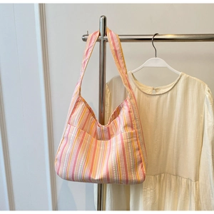 Detail of pink and orange striped pleated nylon tote bag texture on a white wall hanger