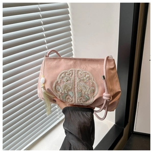 Detail of pink silk fabric with floral embroidery and tassel on the shoulder bag