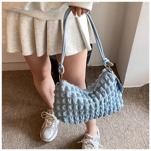 Close-up of light blue bubble textured shoulder bag with heart charm and gold hardware detail