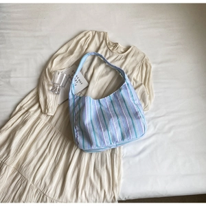Detailed close-up of a striped colorful nylon hobo bag styled on a beige pleated dress
