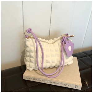 Detail of white bubble texture fabric bag with purple strap and flower pendant charm