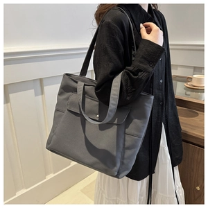 Détail du sac cabas en toile grise avec une poche avant à bouton-pression métallique