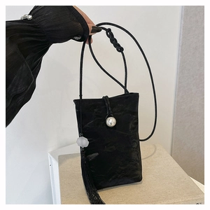 Detail of black silk texture phone bag featuring a pearl clasp and long tassel