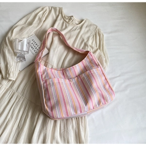 Detail of colorful striped nylon tote bag with front pockets on white linen