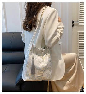 Détail de broderie papillon élégante et gland en soie sur le sac seau bandoulière crème