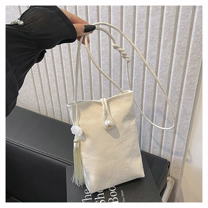Detail of white wrinkled leather crossbody bag with pearl buckle and long tassel charm