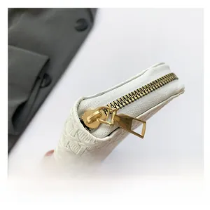 Close-up of white woven texture leather wallet featuring premium gold metal zipper detail