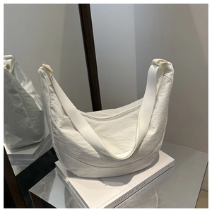 Detail van witte geplooide nylon schoudertas met maanvorm en getextureerde stoffen afwerking