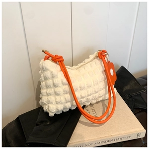 Detail of white bubble pleated bag with bright orange rope handle and floral pendant