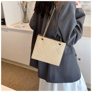 Detail of woven tote bag featuring gold chain strap and premium texture for women