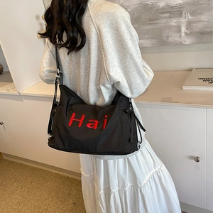 Black canvas tote bag with red Hai embroidery in a minimalist preppy crossbody style