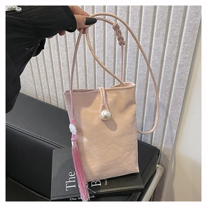 Pink crossbody phone bag with crinkled texture, pearl button and silk tassel details